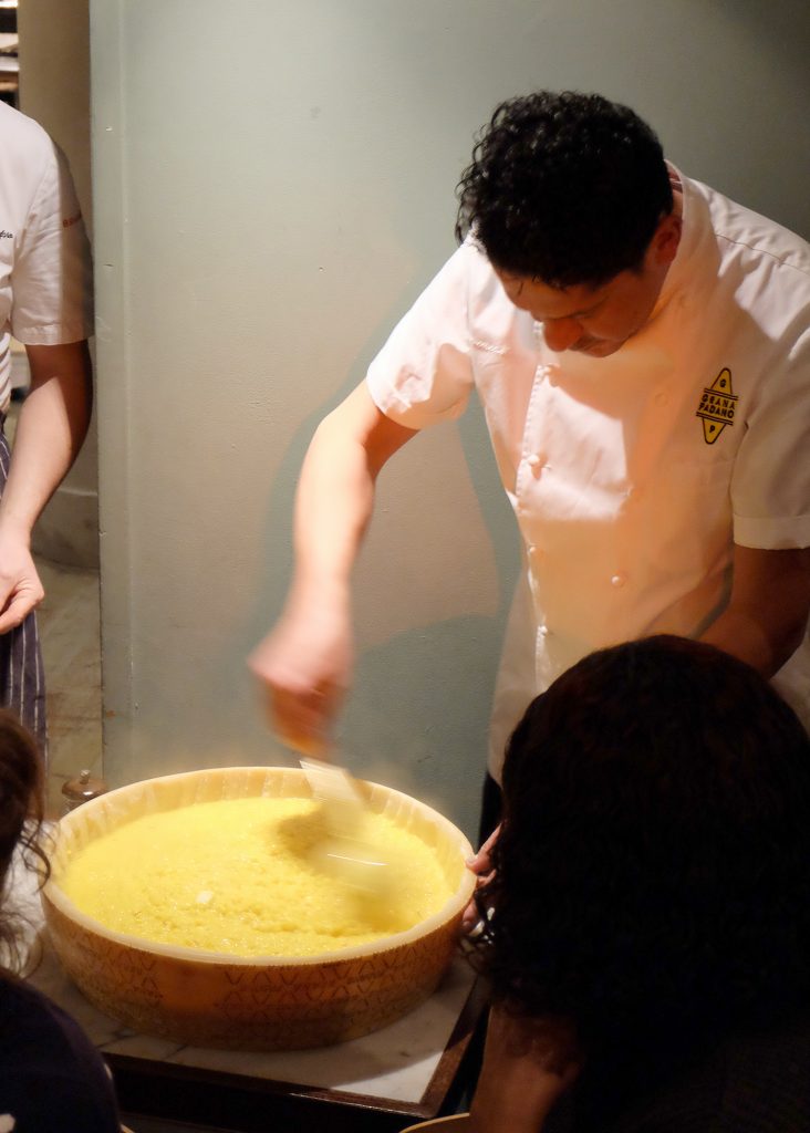Chef mixing risotto in cheese wheel